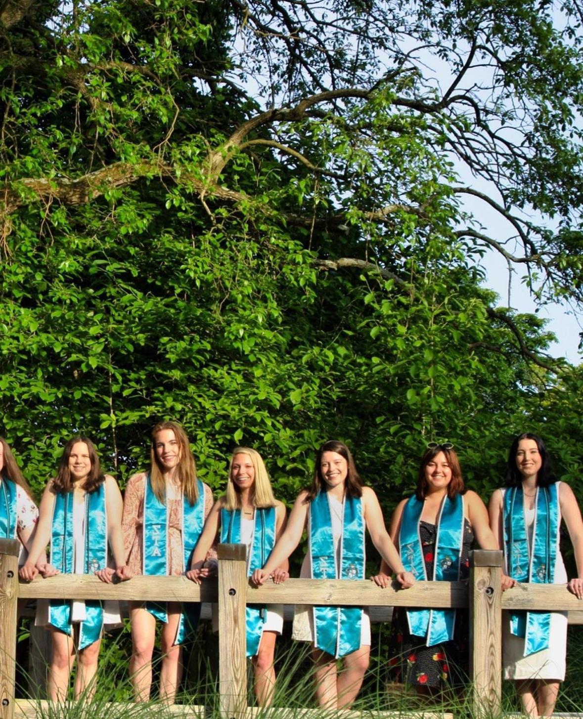 ZTA grads standing on bridge wearing stole 